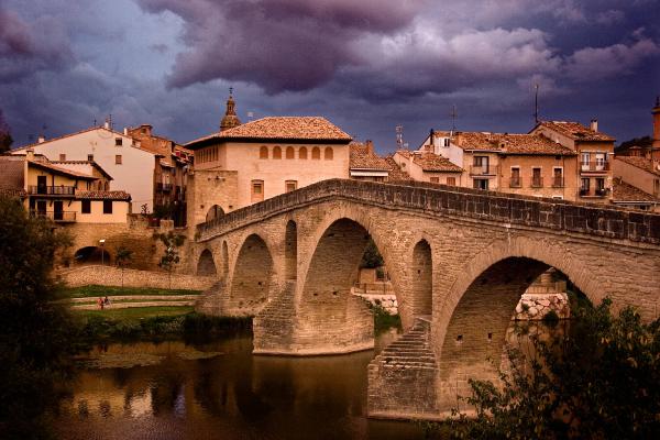 Ilunabarrean zubi erromanikoaren eta Puente la Reina herriaren ikuspegia